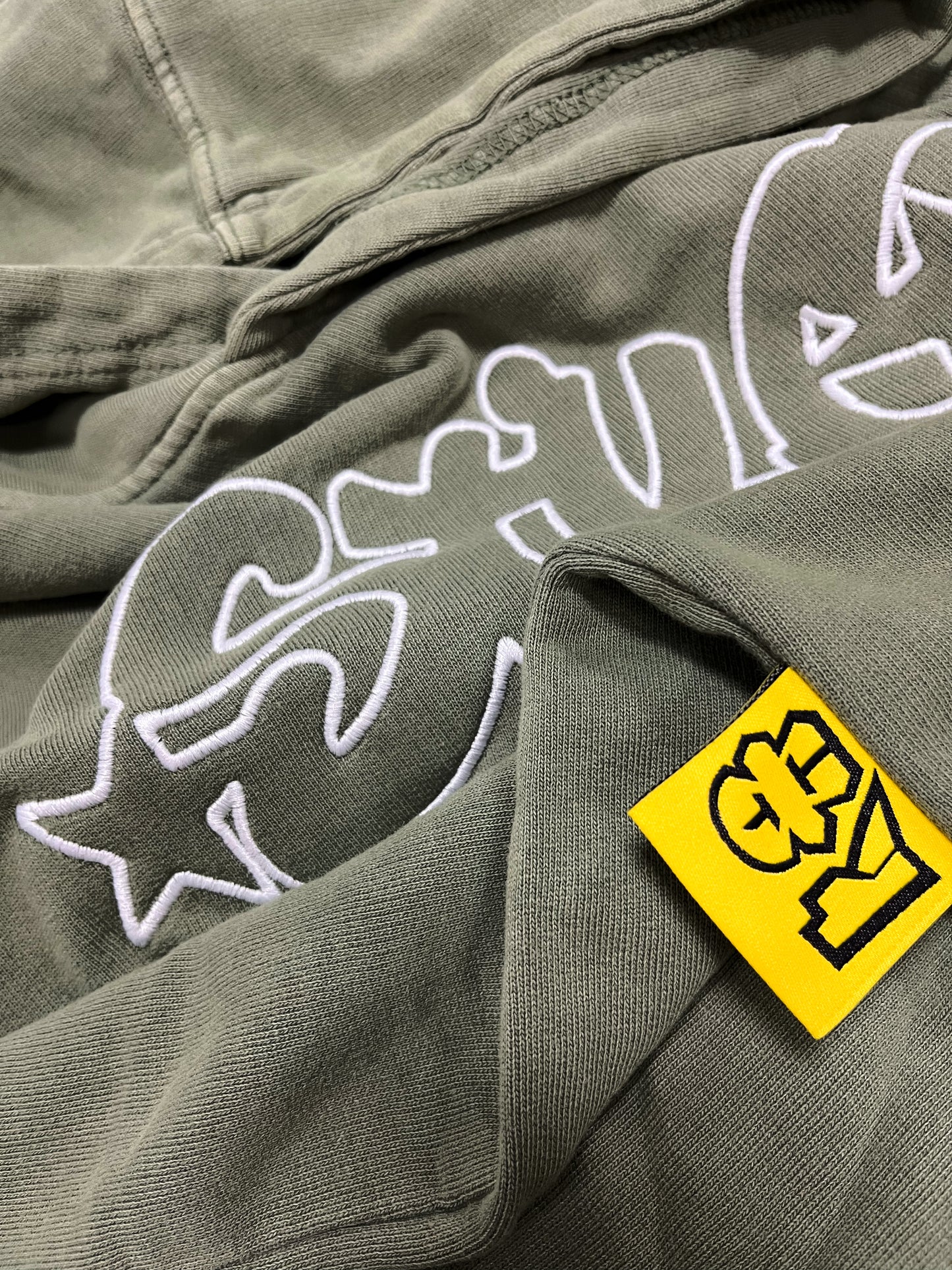 details of a green hoodie, inspired on the clothing of hip hop rappers of the bronx
