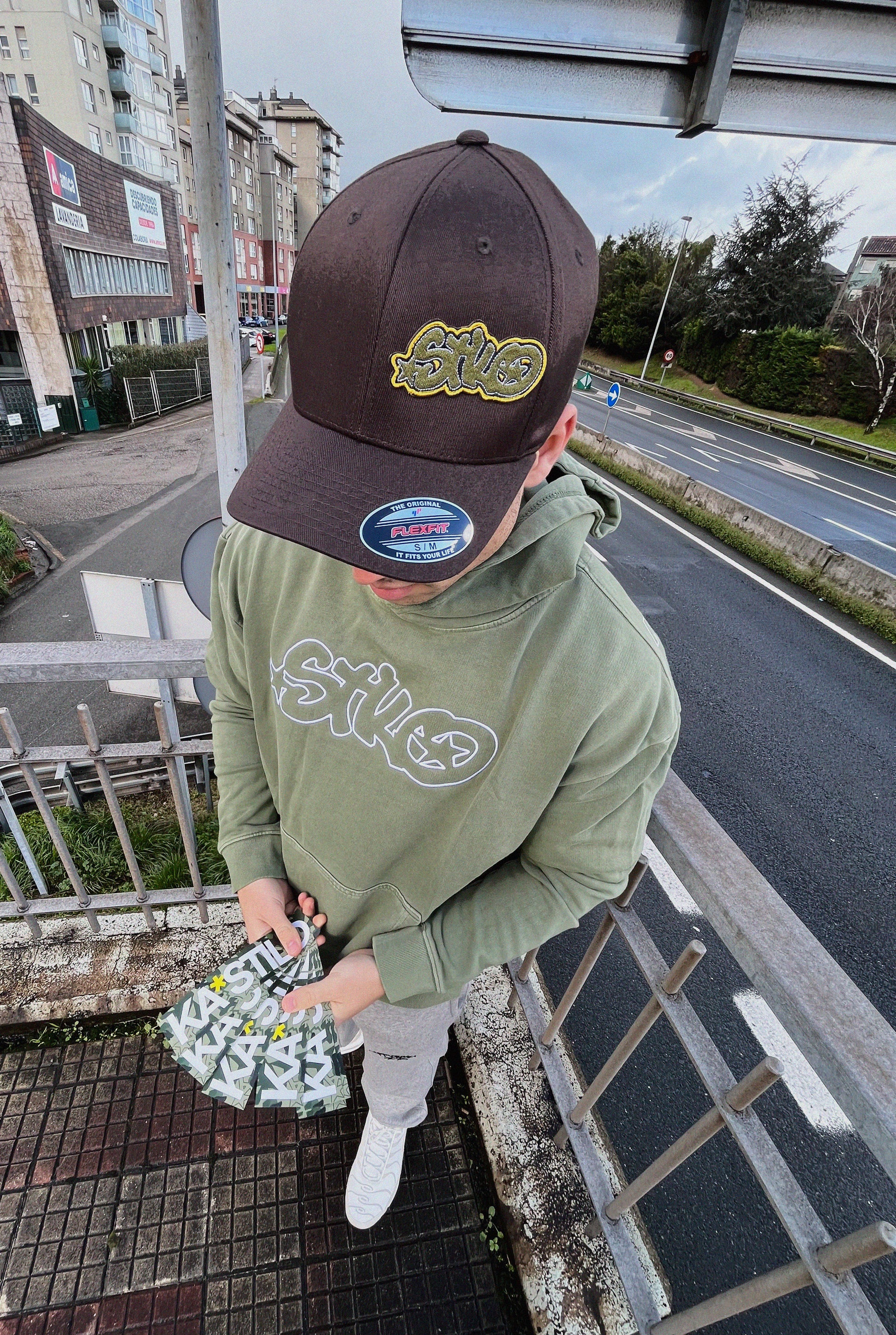 Urban guy showcasing fashionable hat and green hoodie. Great take on streetwear