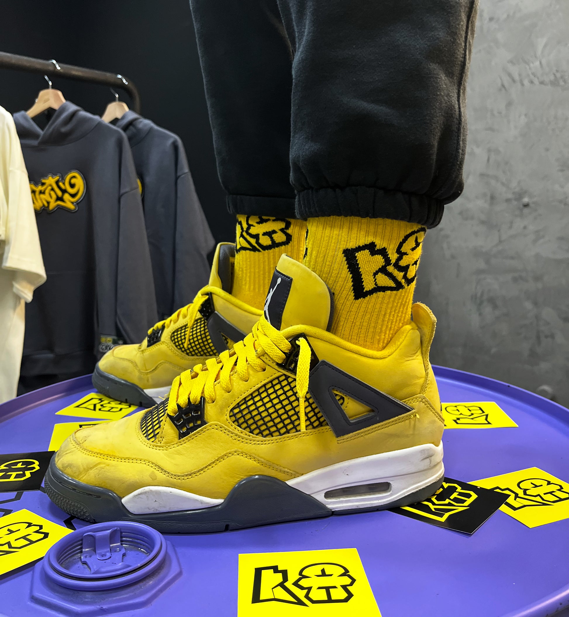 A fashion-forward individual showcases their love for streetwear with eye-catching yellow socks placed on a table. This vibrant pop of color adds a hip-hop flair to their ensemble.